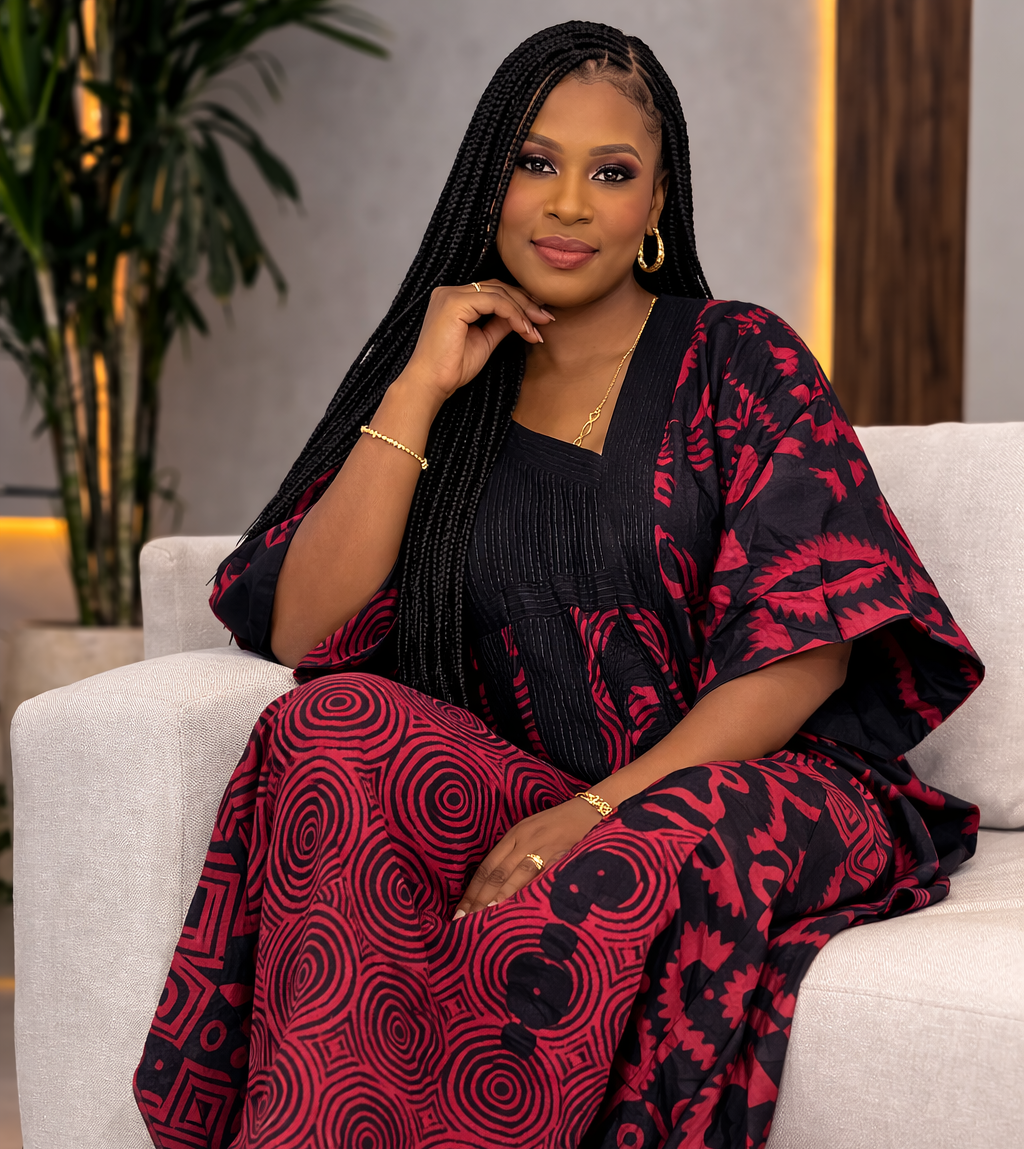 Woman in a red and black patterned outfit sitting on a white couch.