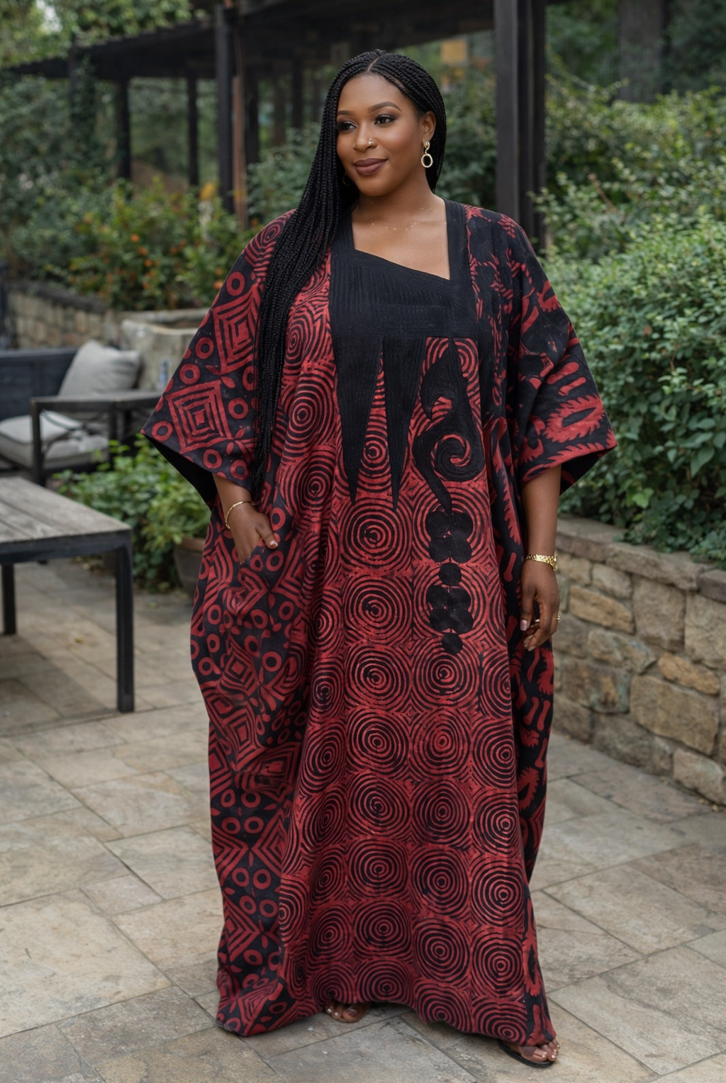 Woman wearing a red and black patterned dress standing outdoors.