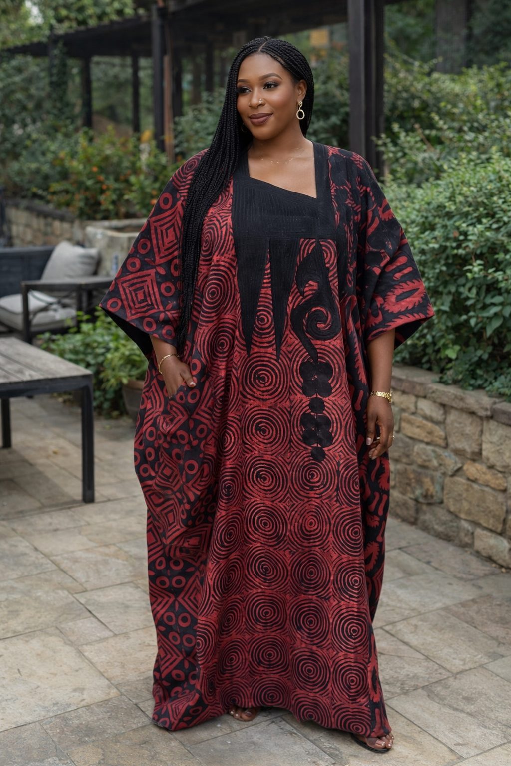 Woman wearing a red and black patterned dress standing outdoors.
