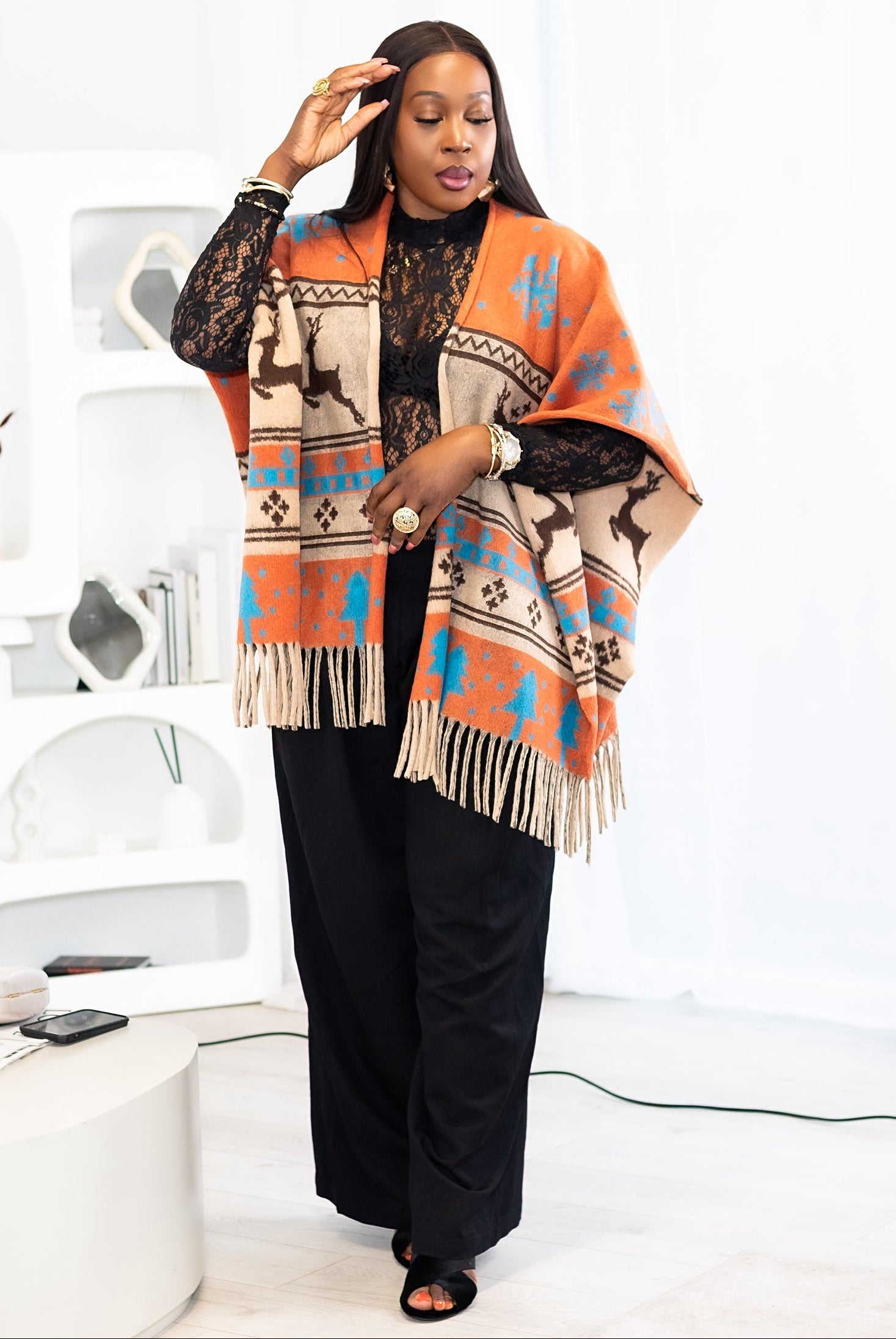 Woman wearing a patterned poncho in a minimal white room