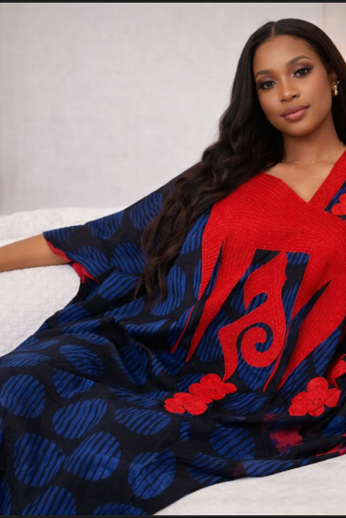 Woman wearing a blue and red patterned dress sitting on a white couch.