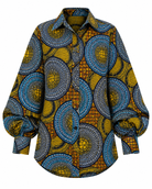 A long-sleeve button-up shirt featuring a bold African wax print pattern with blue, yellow, and black circular motifs, displayed on a clean white background.