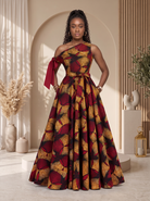 An African model wearing a floor-length off-the-shoulder gown with a bold abstract floral print in deep red, mustard yellow, and brown tones. Asymmetric African Print Maxi dress perfect for any special occasion, African print maxi gown, plus size African fashion UK, puff sleeve maxi dress, colourful summer dress, statement occasion dress, luxury African clothing, vibrant maxi dress for women, African-inspired summer fashion, wedding guest dress UK, Celebrate Black History Month with Culture Dresses