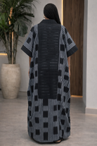 Person wearing a black and white patterned dress in an indoor setting.