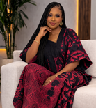 Woman in a red and black patterned outfit sitting on a white couch.