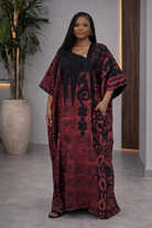 Woman wearing a red and black patterned dress standing indoors.
