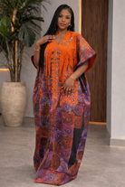 Woman wearing an orange and purple patterned dress indoors.