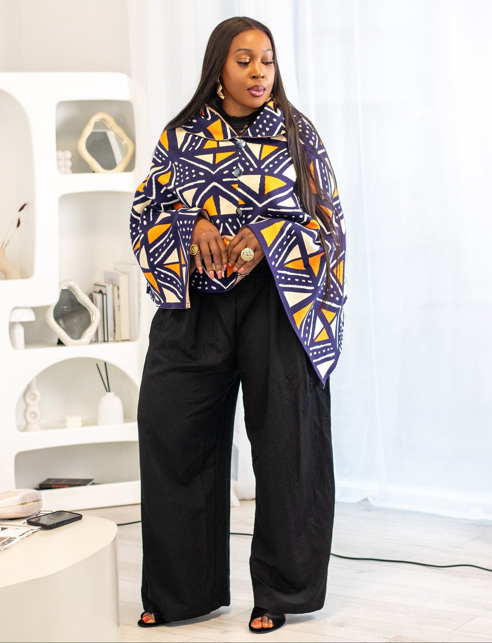 Woman wearing a colorful patterned coat in a modern interior setting