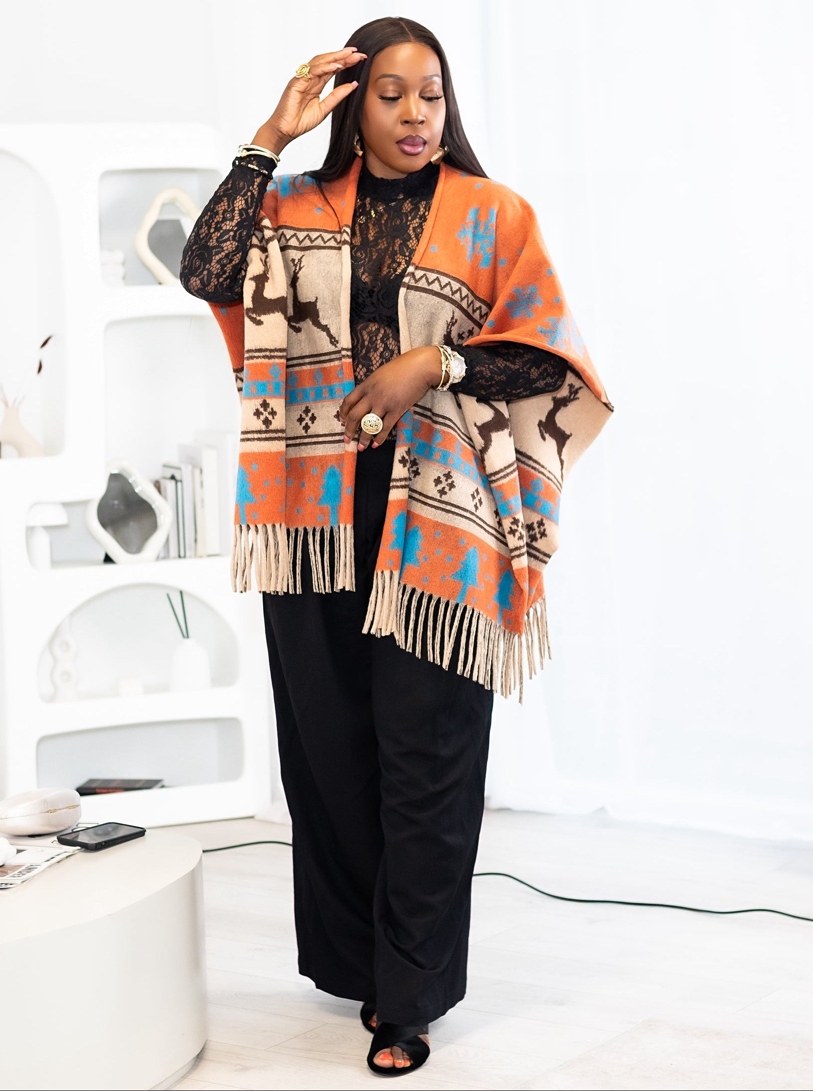 Woman wearing a patterned poncho in a minimal white room