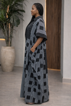 Woman wearing a black and white patterned dress standing indoors.
