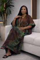 Woman in a patterned dress sitting on a couch with a plant in the background