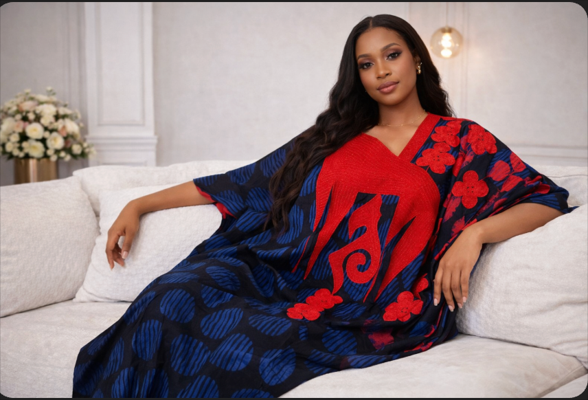 Woman wearing a blue and red patterned dress sitting on a white couch.
