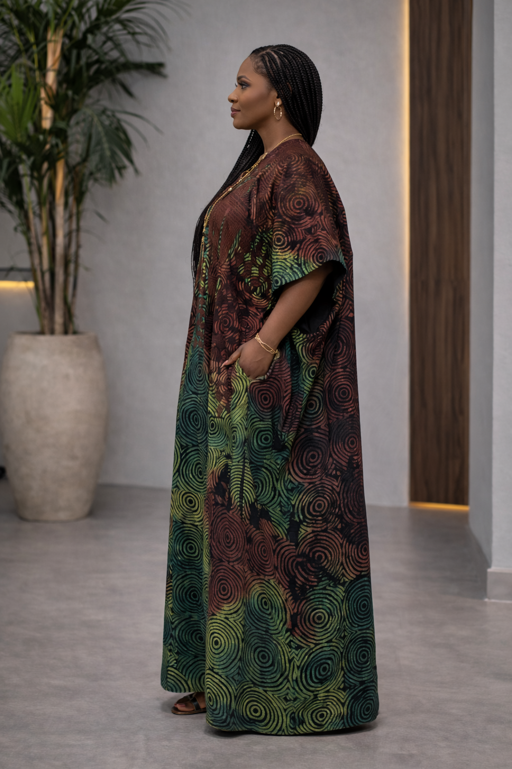 Woman wearing a long, patterned dress standing in a modern indoor setting.